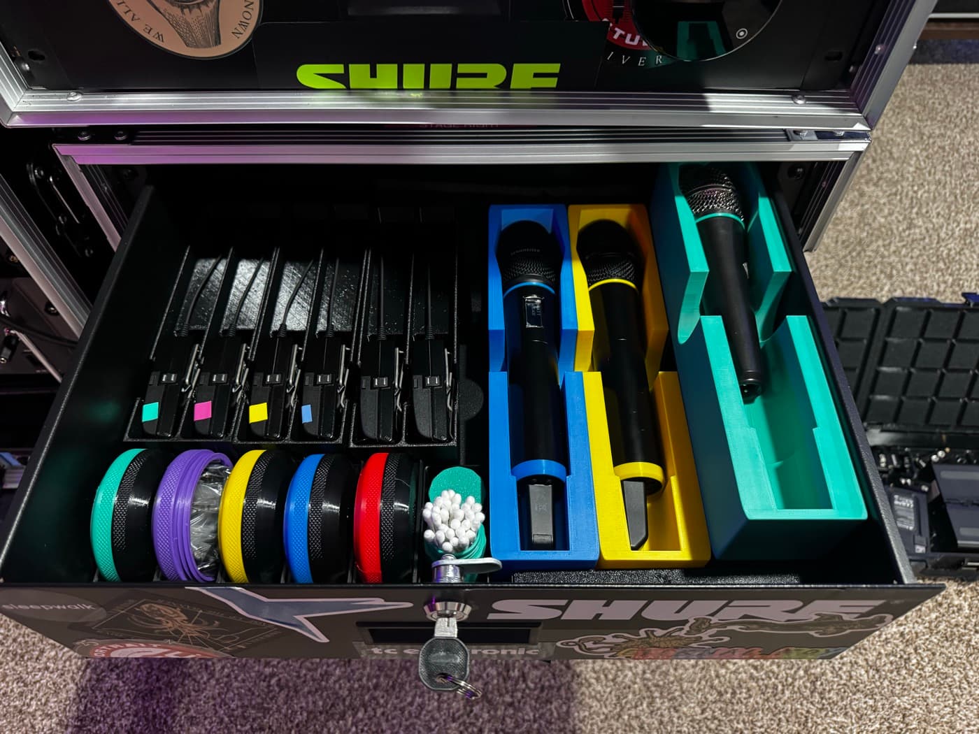 Color-coded wireless microphone packs, microphones, and accessories organized inside Matt's rack drawer